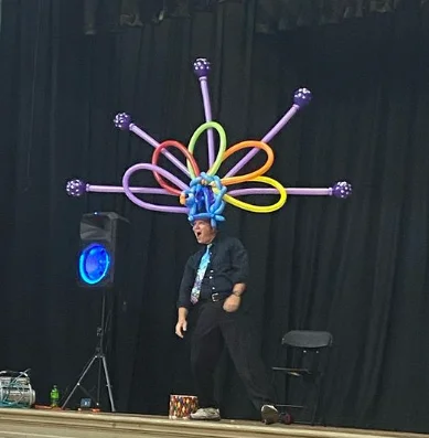 Dale Obrochta onstage wearing a large balloon creation during The Art of Inflation performance