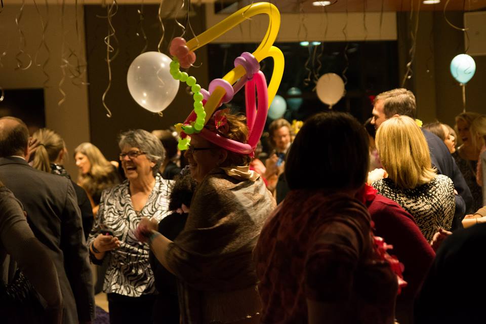Guests laughing and socializing during interactive balloon entertainment at a corporate hospitality reception