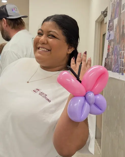 NLX Beverage Solutions employee smiling with a pink and purple balloon butterfly during Safety Week in New Lenox