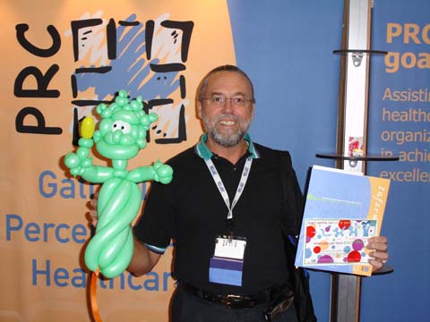 Trade show attendee holding custom balloon artwork and PRC marketing material at a Professional Research Consultants exhibit